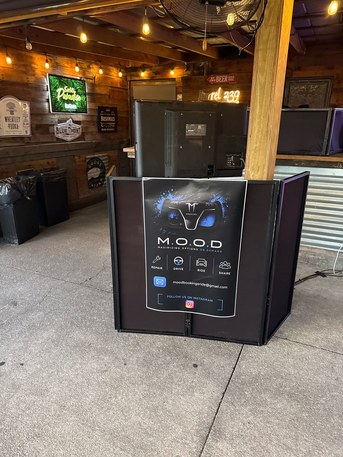 M.O.O.D. poster displayed at an event bar, showing the yoke steering wheel, Repair, Drive, Ride, Share and the booking email